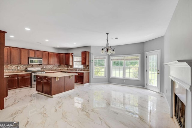 543 Serene Waters Trl, Jonesboro, GA 30236 - kitchen with appliances with stainless steel finishes, a fireplace, a chandelier, backsplash, and light countertops