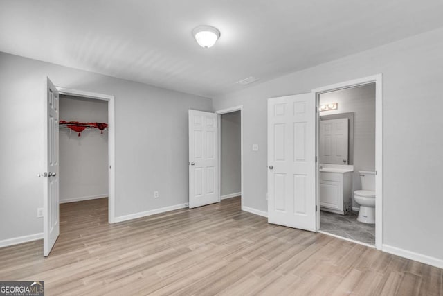 543 Serene Waters Trl, Jonesboro, GA 30236 - unfurnished bedroom with light wood-type flooring, a spacious closet, ensuite bathroom, and a closet