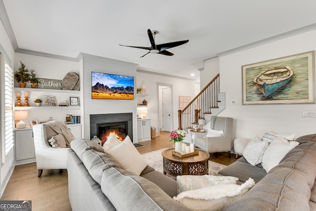 485 Delaperriere Loop, Jefferson, GA 30549 - living area with a ceiling fan, light wood finished floors, a glass covered fireplace, healthy amount of natural light, and ornamental molding