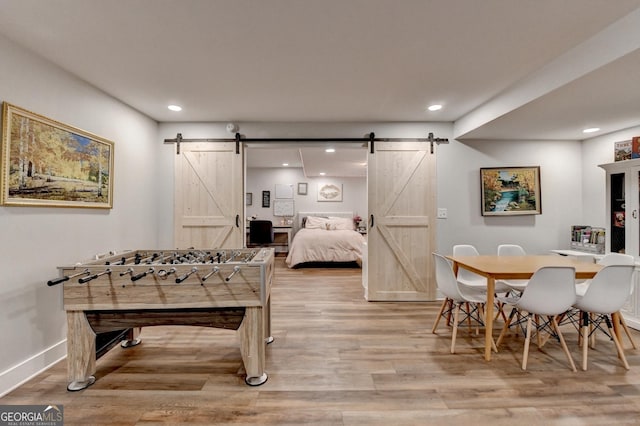 1882 Flowering Dr, Grayson, GA 30017 - bedroom with a barn door, light wood-type flooring, recessed lighting, and baseboards