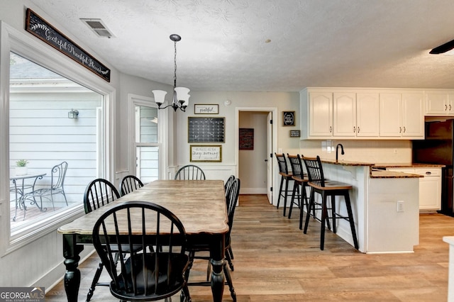 1882 Flowering Dr, Grayson, GA 30017 - dining room with plenty of natural light, a chandelier, light wood-style flooring, a textured ceiling, and baseboards