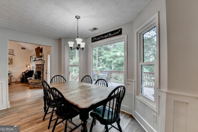 1882 Flowering Dr, Grayson, GA 30017 - dining area featuring a chandelier, a stone fireplace, light wood finished floors, healthy amount of natural light, and a textured ceiling