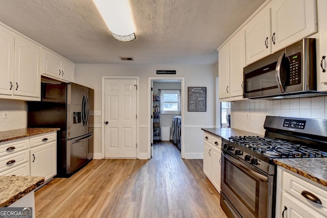 1882 Flowering Dr, Grayson, GA 30017 - kitchen with stainless steel appliances, light wood-style flooring, white cabinets, and a textured ceiling