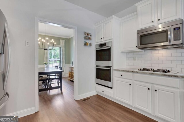 3980 Suwanee Place Dr, Suwanee, GA 30024 - kitchen with appliances with stainless steel finishes, baseboards, a chandelier, backsplash, and white cabinets