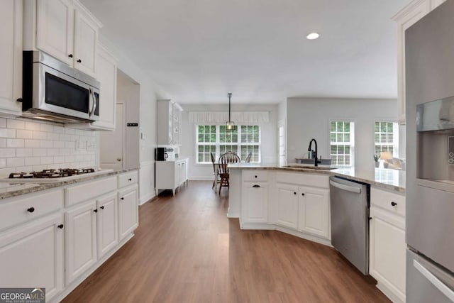 3980 Suwanee Place Dr, Suwanee, GA 30024 - kitchen featuring appliances with stainless steel finishes, a sink, light wood finished floors, decorative backsplash, and white cabinets