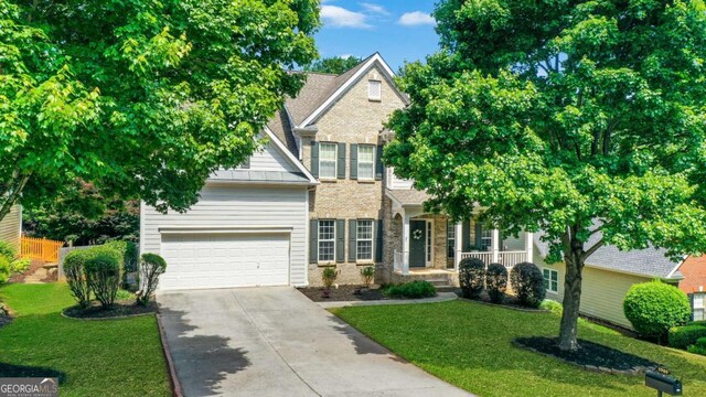 3980 Suwanee Place Dr, Suwanee, GA 30024 - view of front of house with concrete driveway, a front yard, a garage, covered porch, and stone siding