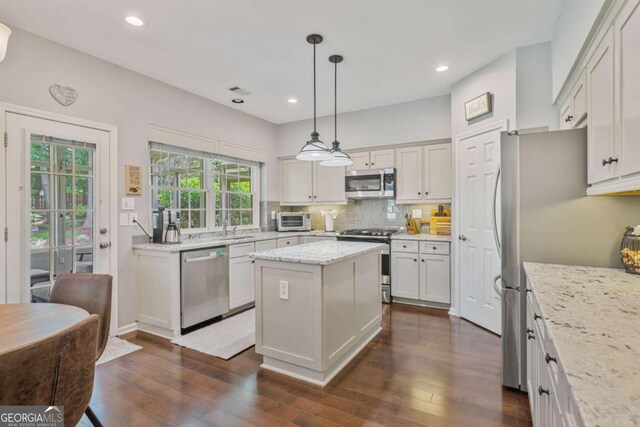 8045 Depford Way, Cumming, GA 30041 - kitchen with appliances with stainless steel finishes, tasteful backsplash, dark wood-style flooring, a center island, and light stone counters