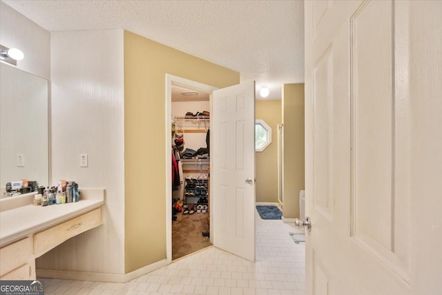 160 Country Mill Ln, Stockbridge, GA 30281 - full bathroom featuring tile patterned floors, a textured ceiling, vanity, baseboards, and a spacious closet