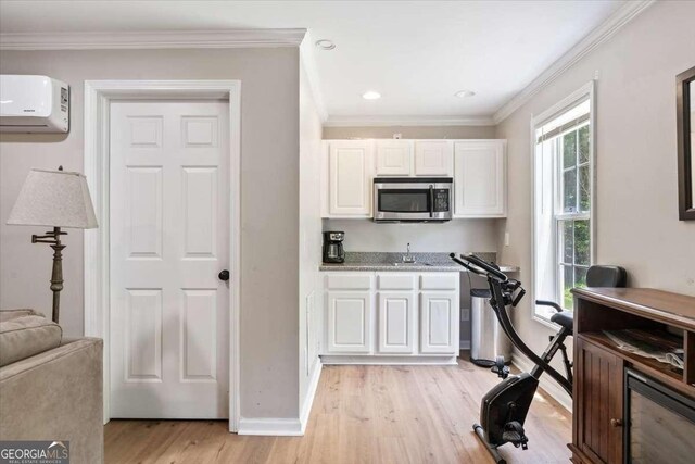 242 Sandhurst Ct, Suwanee, GA 30024 - kitchen with stainless steel microwave, an AC wall unit, a sink, white cabinetry, and light wood-style flooring