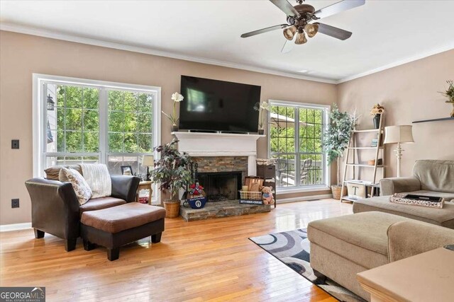 242 Sandhurst Ct, Suwanee, GA 30024 - living room featuring hardwood / wood-style floors, a stone fireplace, a ceiling fan, crown molding, and baseboards
