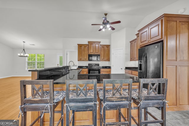 464 Old Camp Creek Rd, Cornelia, GA 30531 - kitchen featuring black appliances, dark countertops, ceiling fan, a center island with sink, and brown cabinets