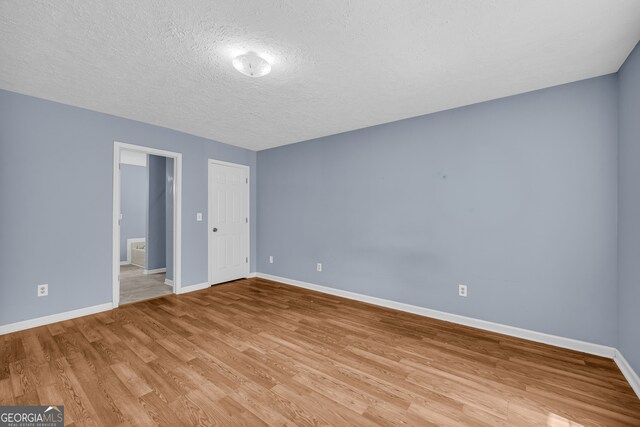 464 Old Camp Creek Rd, Cornelia, GA 30531 - unfurnished bedroom featuring baseboards, light wood-style flooring, a textured ceiling, and ensuite bath