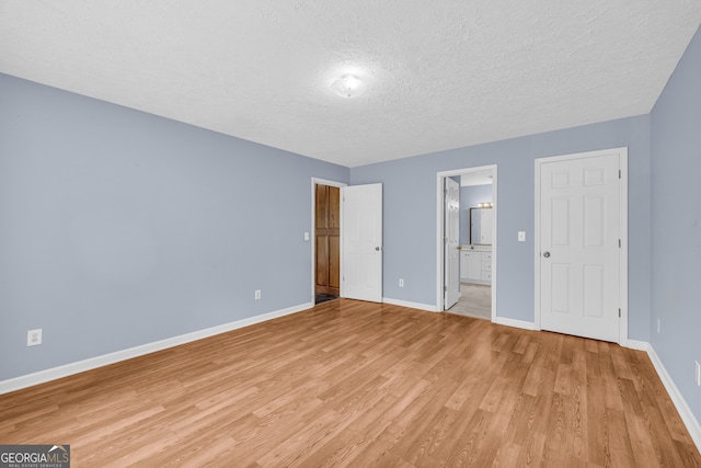 464 Old Camp Creek Rd, Cornelia, GA 30531 - unfurnished bedroom with a textured ceiling, baseboards, light wood-type flooring, and ensuite bath