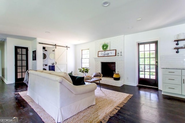 6715 Wright Rd, Sandy Springs, GA 30328 - living room with stacked washing machine and dryer, a barn door, dark wood finished floors, and a fireplace