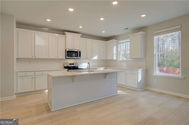 2525 Dixon Pl, Lawrenceville, GA 30045 - kitchen featuring stainless steel appliances, a sink, light countertops, decorative backsplash, and light wood-style flooring