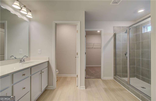 2525 Dixon Pl, Lawrenceville, GA 30045 - full bath featuring vanity, a shower stall, toilet, a spacious closet, and wood finished floors