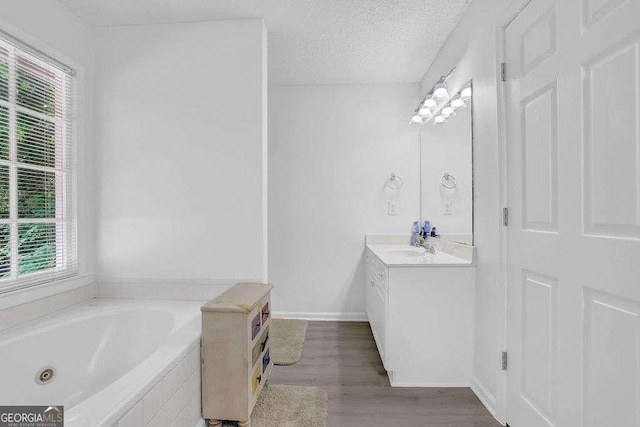 985 Laurel Springs Ln, Marietta, GA 30064 - bathroom featuring vanity, healthy amount of natural light, a jetted tub, a textured ceiling, and wood finished floors