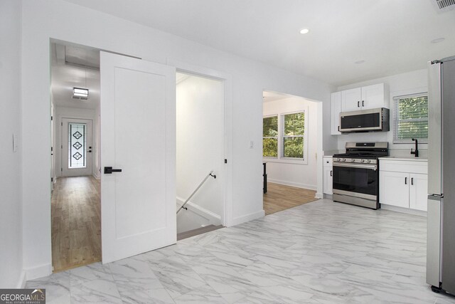 2537 Baker Rd NW, Atlanta, GA 30318 - kitchen with stainless steel appliances, light marble finish flooring, plenty of natural light, white cabinets, and recessed lighting