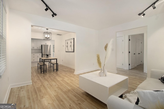 2537 Baker Rd NW, Atlanta, GA 30318 - living room featuring track lighting, light wood-style flooring, baseboards, and a chandelier