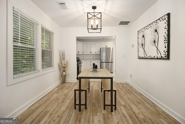 2537 Baker Rd NW, Atlanta, GA 30318 - kitchen with freestanding refrigerator, white cabinetry, light wood-style flooring, baseboards, and a chandelier