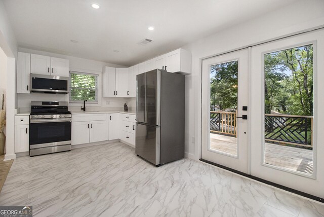 2537 Baker Rd NW, Atlanta, GA 30318 - kitchen with stainless steel appliances, a sink, light countertops, white cabinets, and light marble finish flooring