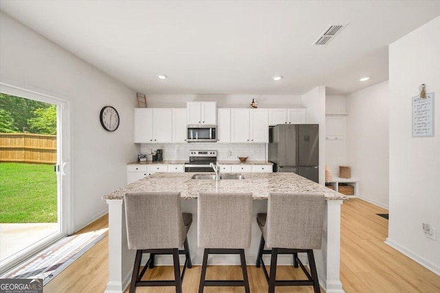 218 Lookout Dr, Dallas, GA 30132 - kitchen with stainless steel appliances, a kitchen island with sink, white cabinetry, a kitchen bar, and tasteful backsplash