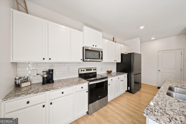 218 Lookout Dr, Dallas, GA 30132 - kitchen with appliances with stainless steel finishes, white cabinetry, light wood-style floors, tasteful backsplash, and recessed lighting