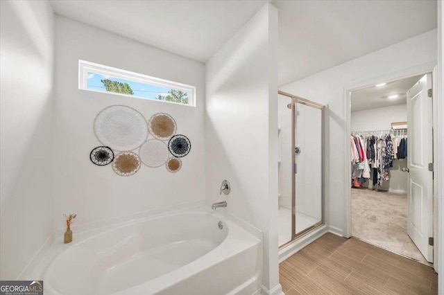 218 Lookout Dr, Dallas, GA 30132 - bathroom featuring a bath, a stall shower, a spacious closet, and wood finished floors