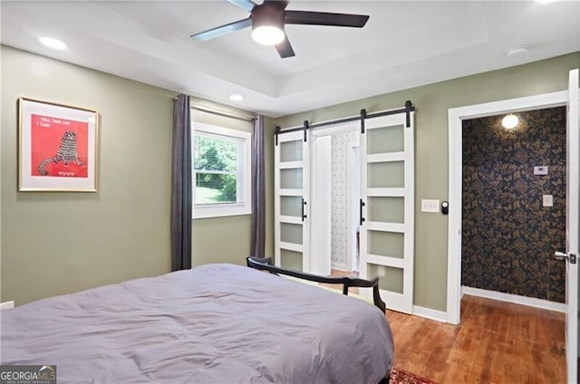 1202 Key Rd SE, Atlanta, GA 30316 - bedroom featuring a barn door, wood finished floors, a raised ceiling, baseboards, and ceiling fan