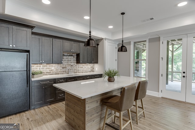 4781 Falling Brook Dr, Flowery Branch, GA 30542 - kitchen featuring freestanding refrigerator, light wood-style floors, tasteful backsplash, light countertops, and a kitchen island