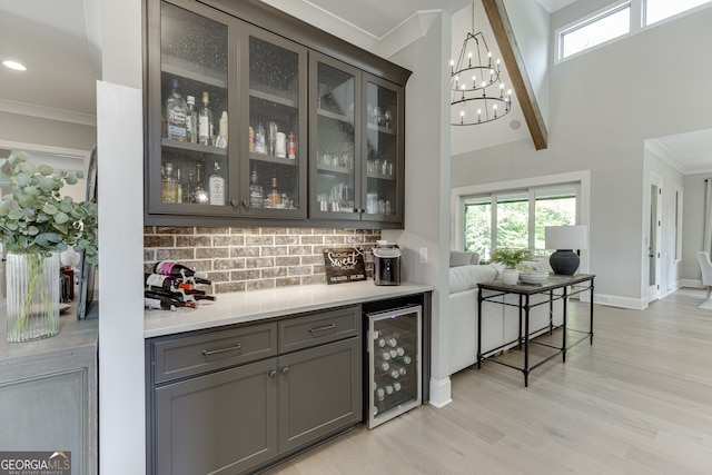 4781 Falling Brook Dr, Flowery Branch, GA 30542 - bar area featuring wine cooler, tasteful backsplash, light wood finished floors, crown molding, and a chandelier