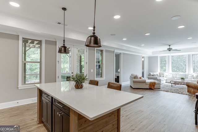 4781 Falling Brook Dr, Flowery Branch, GA 30542 - kitchen featuring light wood-type flooring, baseboards, light countertops, open floor plan, and hanging light fixtures