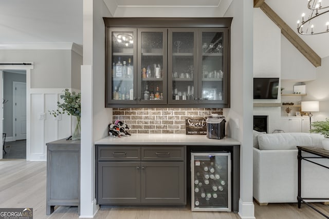 4781 Falling Brook Dr, Flowery Branch, GA 30542 - indoor dry bar featuring beverage cooler, light wood-style flooring, ornamental molding, a chandelier, and tasteful backsplash