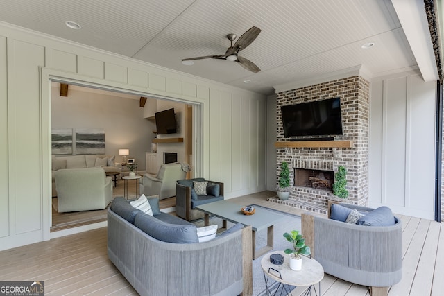 4781 Falling Brook Dr, Flowery Branch, GA 30542 - living room featuring a fireplace, ornamental molding, light wood finished floors, ceiling fan, and a decorative wall
