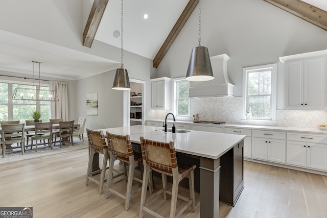 4781 Falling Brook Dr, Flowery Branch, GA 30542 - kitchen with custom range hood, light wood finished floors, light countertops, decorative backsplash, and beam ceiling