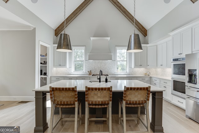 4781 Falling Brook Dr, Flowery Branch, GA 30542 - kitchen with stainless steel appliances, custom range hood, an island with sink, light countertops, and a kitchen bar