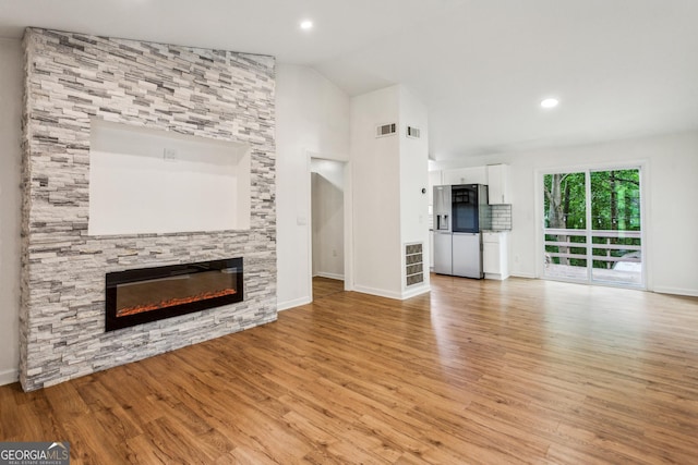 232 Apple Branch Dr, Woodstock, GA 30188 - unfurnished living room featuring a stone fireplace, light wood-style flooring, baseboards, lofted ceiling, and recessed lighting