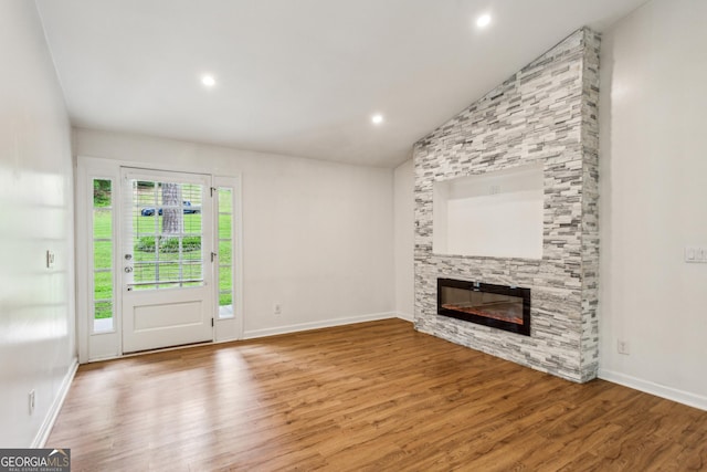 232 Apple Branch Dr, Woodstock, GA 30188 - unfurnished living room featuring a stone fireplace, wood finished floors, lofted ceiling, recessed lighting, and baseboards