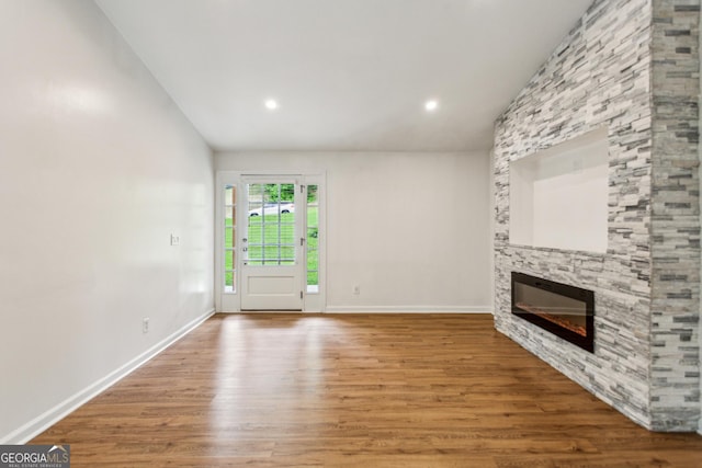 232 Apple Branch Dr, Woodstock, GA 30188 - unfurnished living room with lofted ceiling, wood finished floors, a stone fireplace, baseboards, and recessed lighting