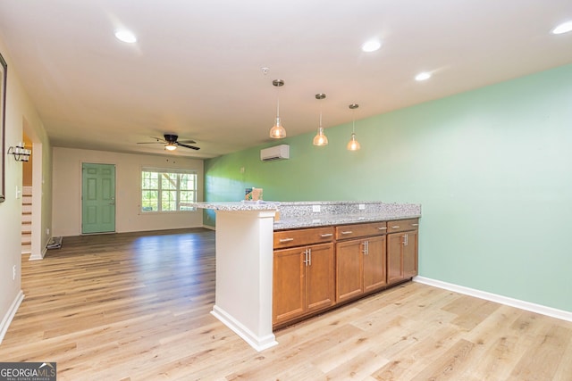 111 Portico Pl, Newnan, GA 30265 - kitchen with a wall unit AC, a ceiling fan, brown cabinetry, light wood finished floors, and a peninsula