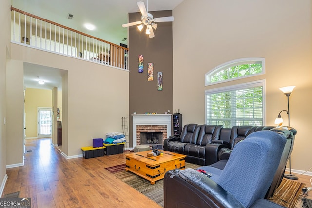 111 Portico Pl, Newnan, GA 30265 - living room featuring a high ceiling, hardwood / wood-style flooring, baseboards, ceiling fan, and a brick fireplace
