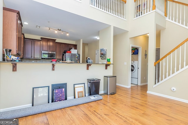 111 Portico Pl, Newnan, GA 30265 - kitchen with appliances with stainless steel finishes, a kitchen breakfast bar, baseboards, and light wood-style floors