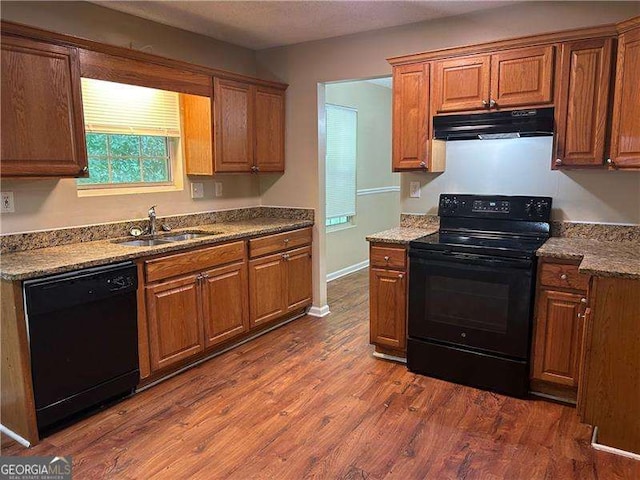 6536 Rebecca Lou Ln, Lithonia, GA 30058 - kitchen featuring black appliances, under cabinet range hood, dark wood-type flooring, and brown cabinetry