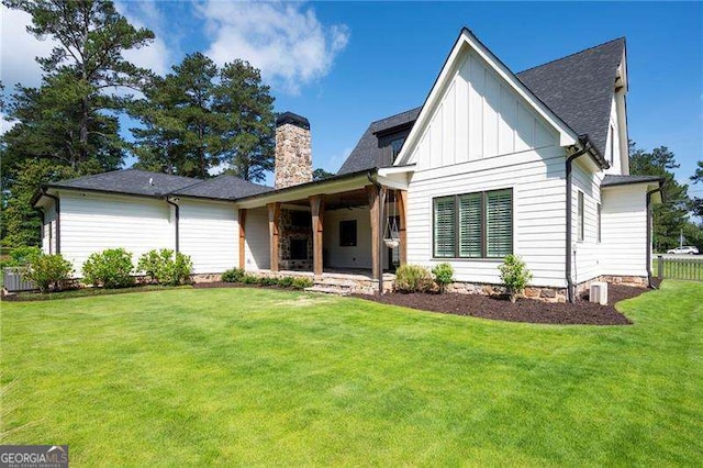 1830 Maple St, Carrollton, GA 30117 - rear view of house featuring board and batten siding, a chimney, a yard, and a shingled roof
