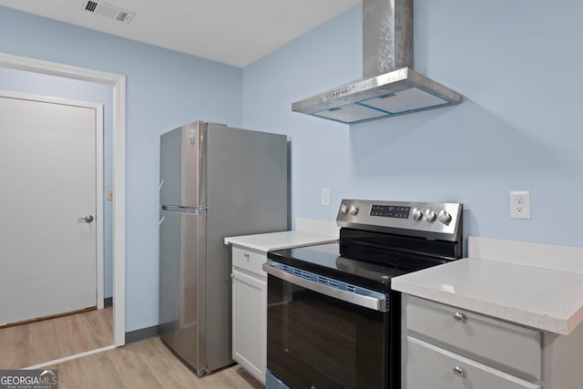 226 Old Atlanta Rd, Stockbridge, GA 30281 - kitchen with stainless steel appliances, wall chimney exhaust hood, light wood-style flooring, light countertops, and white cabinets