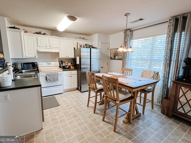 105 Sheffield Dr, Carrollton, GA 30117 - kitchen featuring freestanding refrigerator, electric range, under cabinet range hood, dark countertops, and a textured ceiling