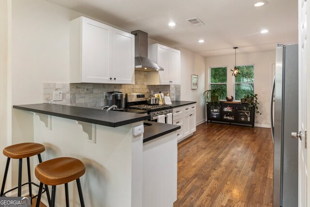 429 Deckner Ave SW, Atlanta, GA 30310 - kitchen featuring wall chimney exhaust hood, stainless steel appliances, dark countertops, a peninsula, and decorative backsplash