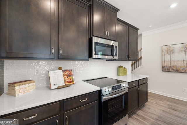 237 Orion Dr, Dalton, GA 30720 - kitchen with appliances with stainless steel finishes, crown molding, dark brown cabinets, light countertops, and light wood-style floors