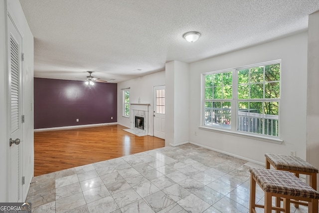 3524 Forest Downs Cv, Decatur, GA 30034 - unfurnished living room with plenty of natural light, baseboards, a ceiling fan, wood finished floors, and a textured ceiling