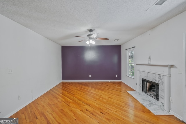 3524 Forest Downs Cv, Decatur, GA 30034 - unfurnished living room featuring a ceiling fan, light wood-style floors, a textured ceiling, a premium fireplace, and baseboards